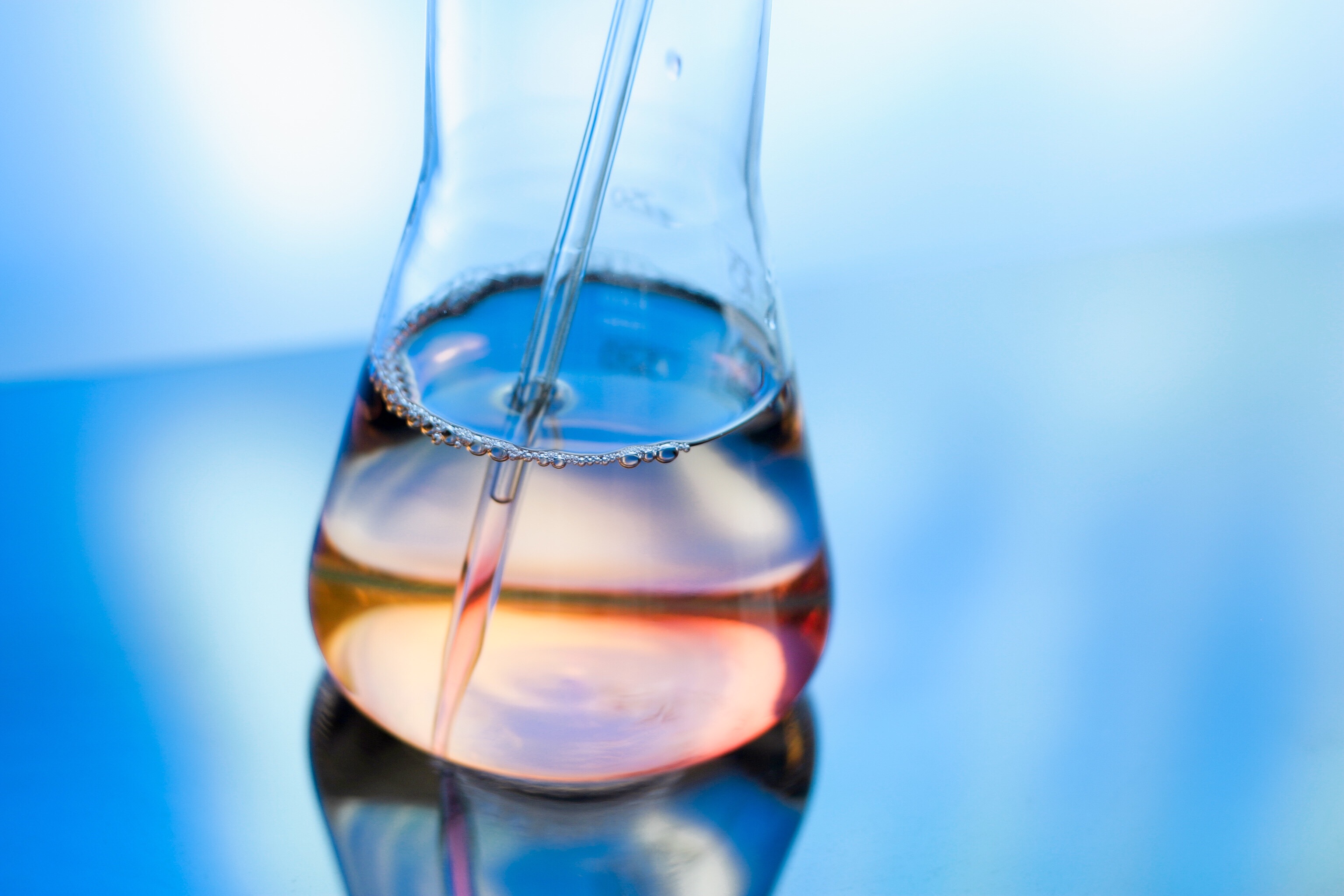 An image of laboratory glassware that has liquid in it on a reflective surface.